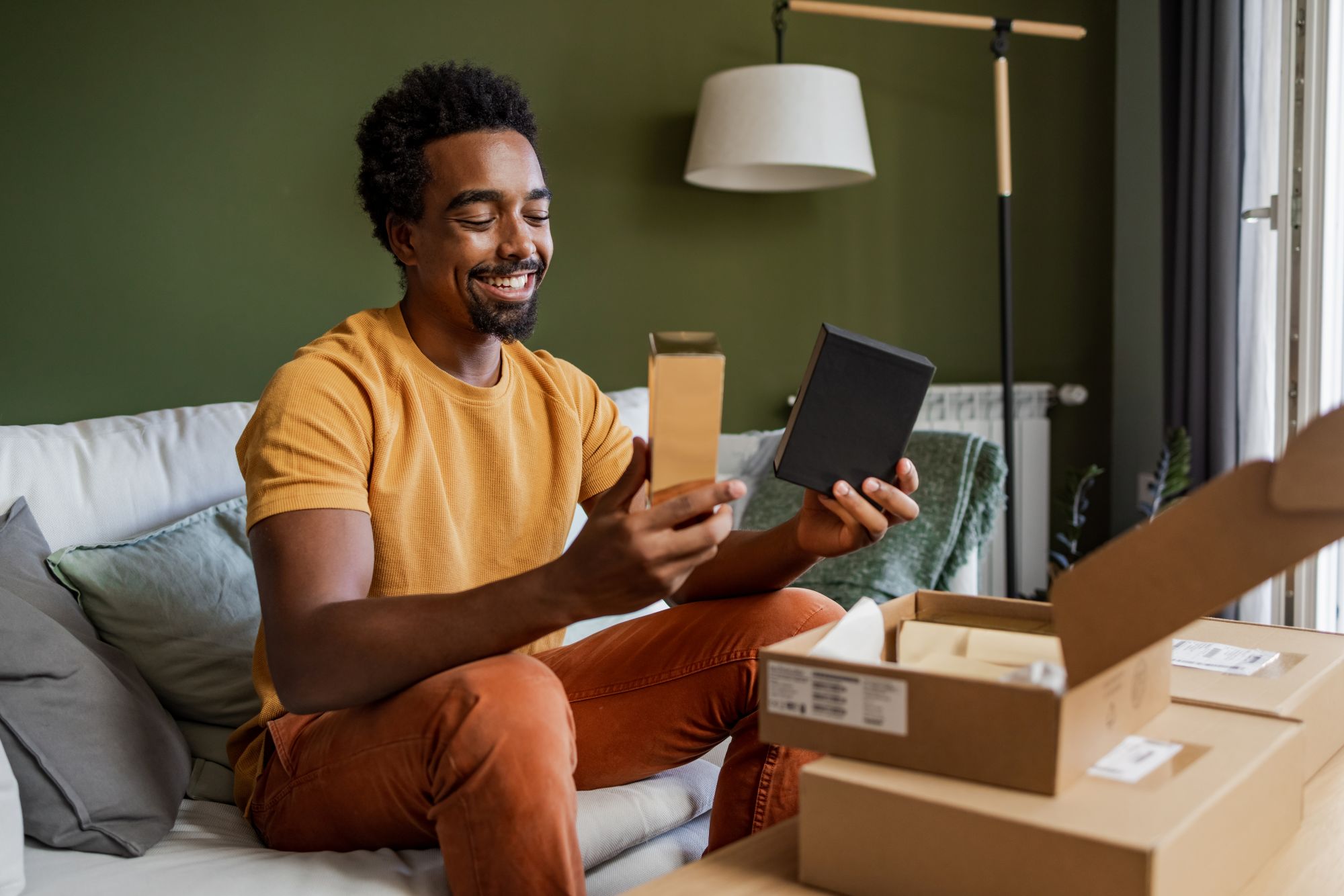 Smiling man opening up cardbard shipping box with items he purchased inside it.

Keyword: Love Paper
