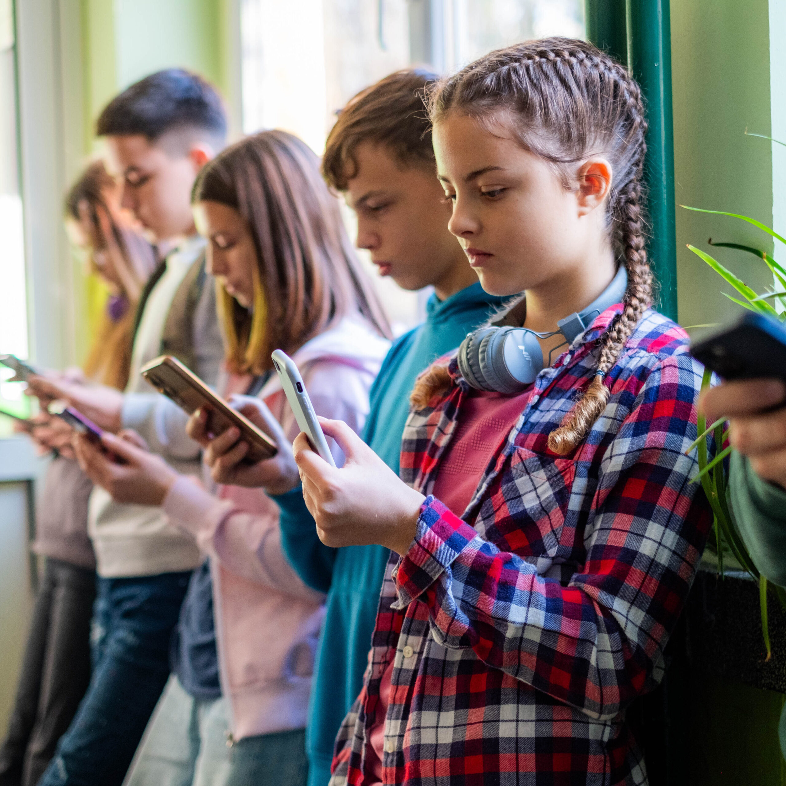 Middle school students staring at their phones in the hall at school.
keyword: Learning